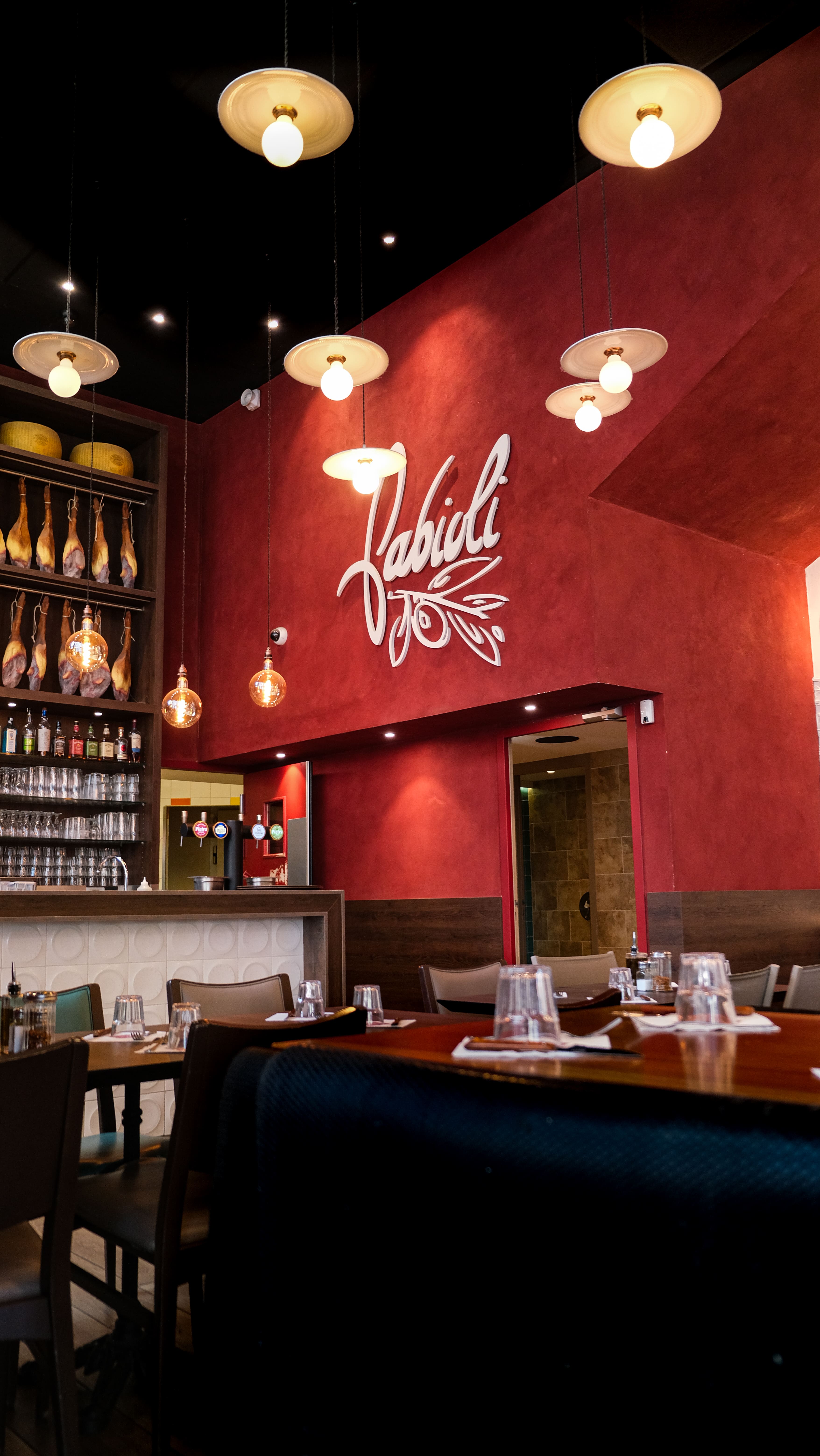Salle du restaurant Fabioli, mur rouge et logo Fabioli au-dessus du bar